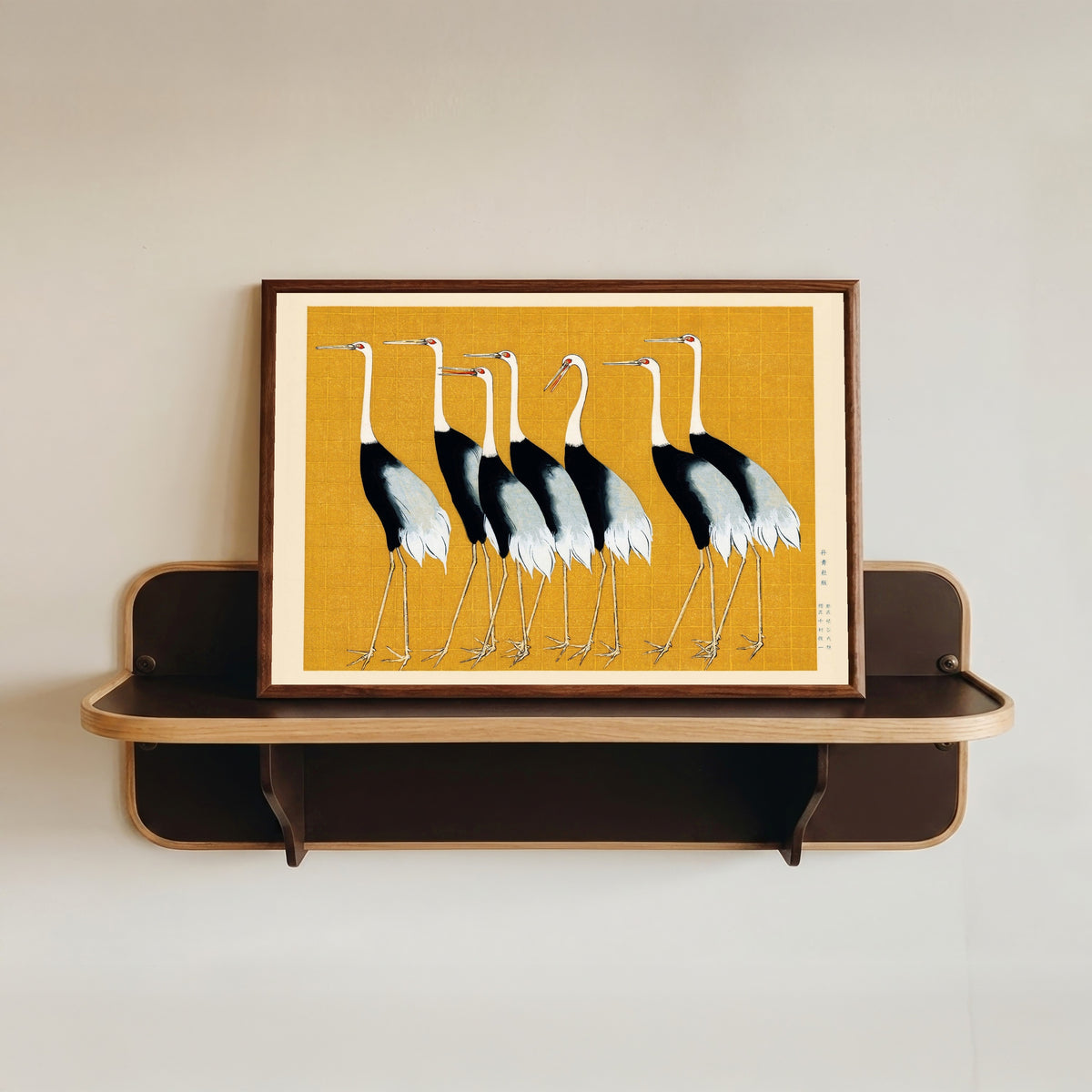 Framed art print of Cranes by Ogata Korin, in a dark wood frame resting on a wall shelf
