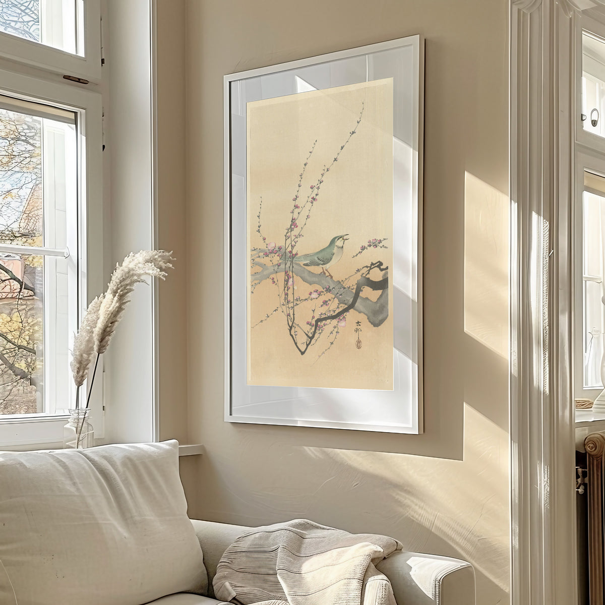Songbird and Plum Blossom by Ohara Koson — framed in a sunlit living room above a sofa