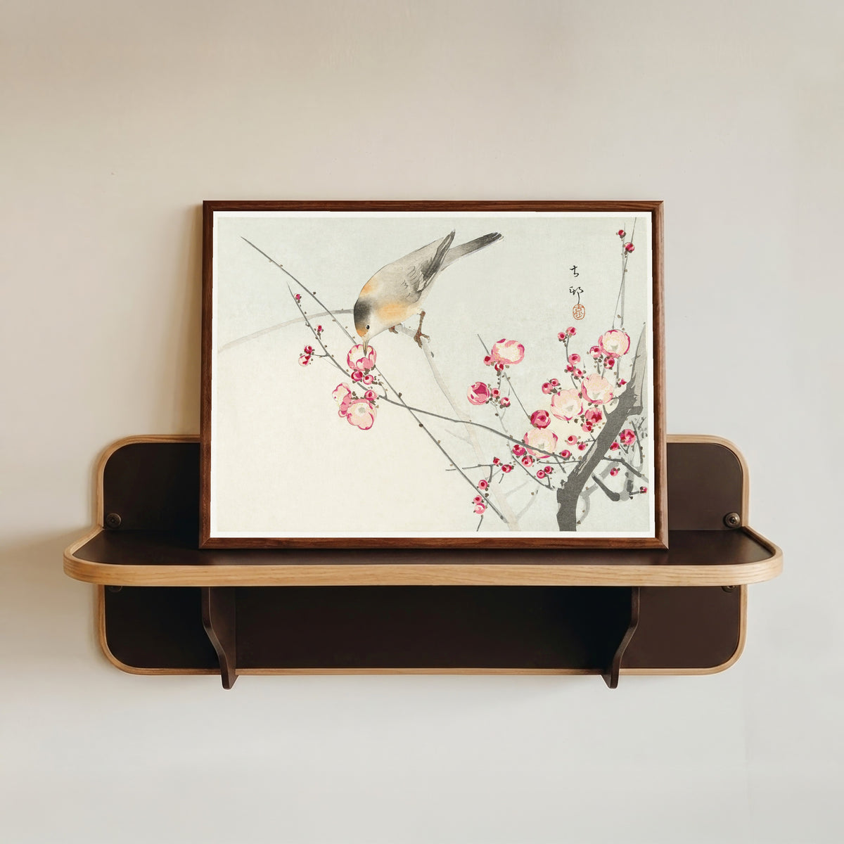 Framed art print of Songbird on Blossom Branch by Ohara Koson, in a dark wood frame resting on a wall shelf
