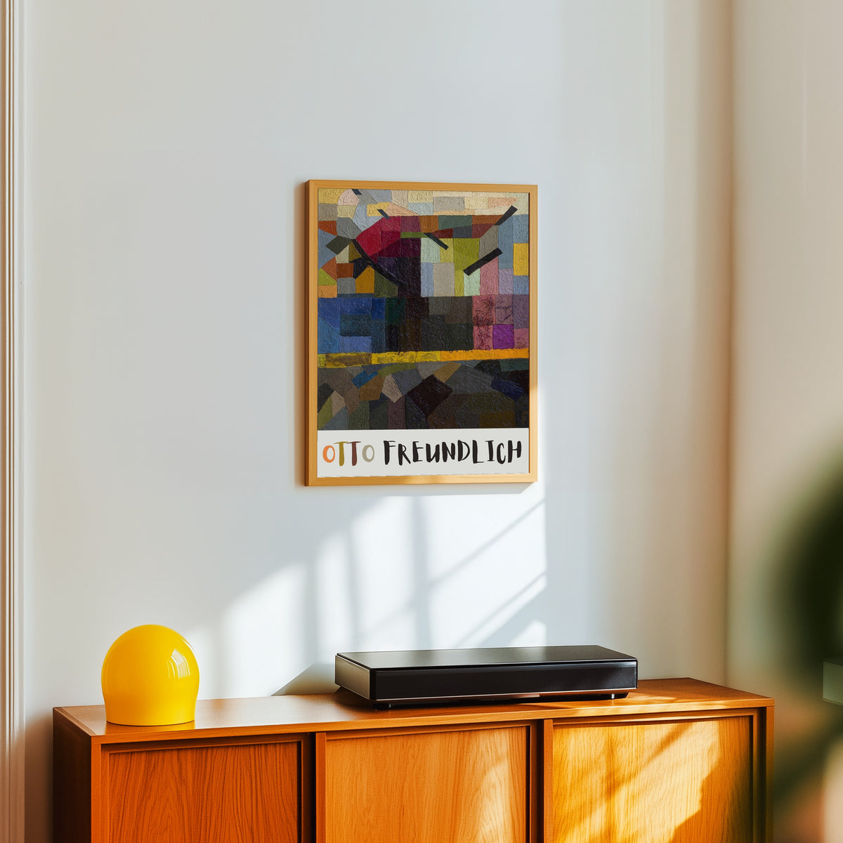 Framed art print of A Tree by Otto Freundlich, in a light wood frame on a white wall above an orange sideboard