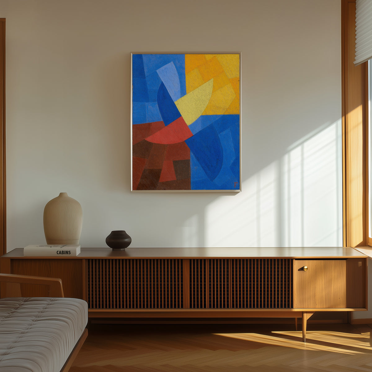Framed art print of Composition (c. 1932) by Otto Freundlich, in a thin light frame on a sunlit wall above a wooden sideboard