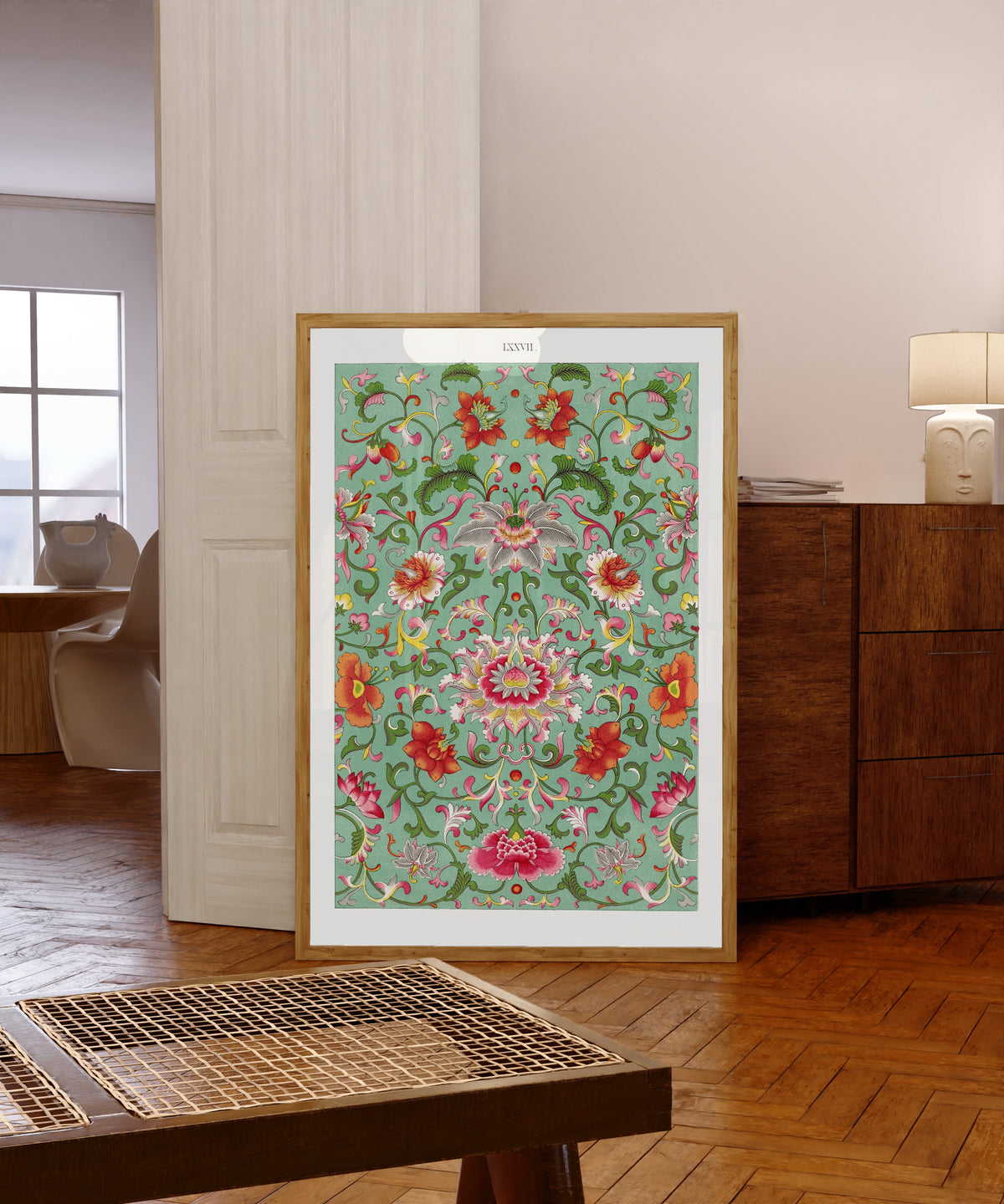Framed art print of Example of Chinese Ornament, Plate 77 by Owen Jones, in a light wood frame leaning in a warm room with a parquet floor