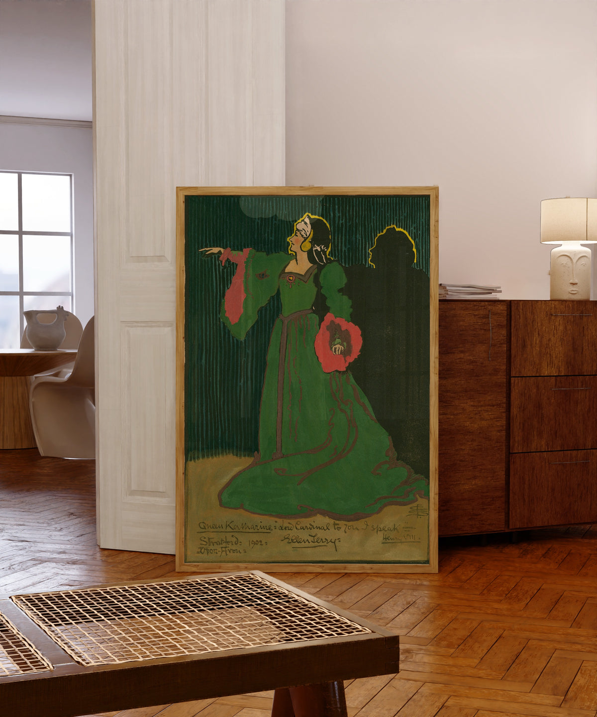 Framed art print of Henry VIII: Ellen Terry as Queen Katharine by Pamela Colman Smith, in a light wood frame leaning in a warm room with a parquet floor