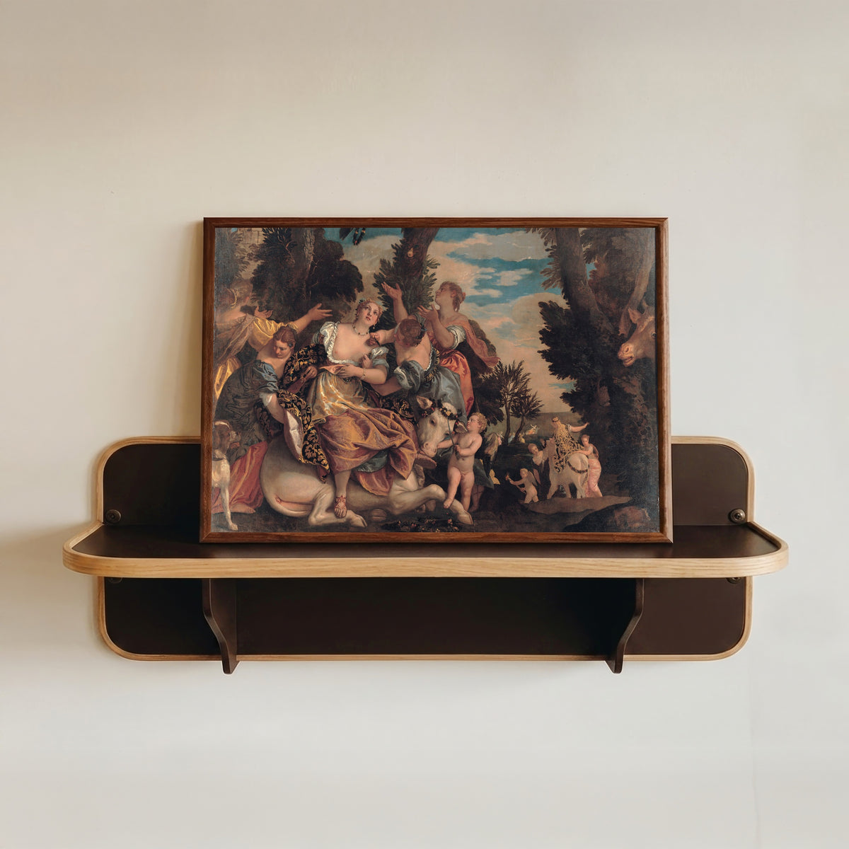 Framed art print of Rape of Europa by Paolo Veronese, in a dark wood frame resting on a wall shelf