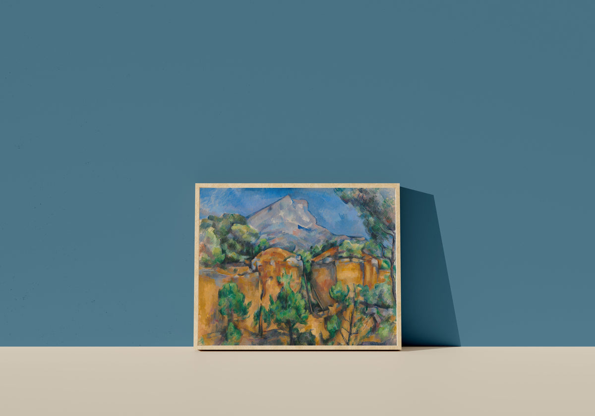 Framed art print of Mont Sainte-Victoire Seen from the Bibémus Quarry by Paul Cezanne, in a light wood frame leaning on a blue wall
