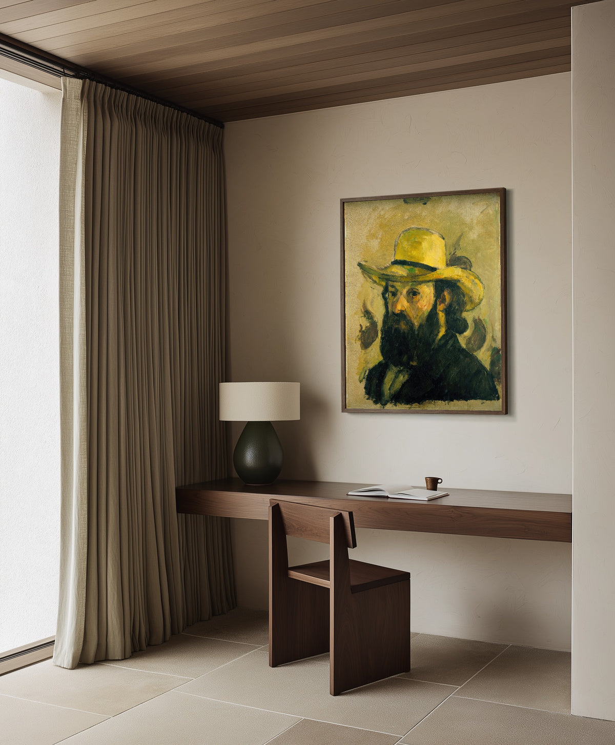 Framed art print of Self-Portrait in a Straw Hat by Paul Cezanne, in a dark wood frame on a plaster wall above a walnut desk