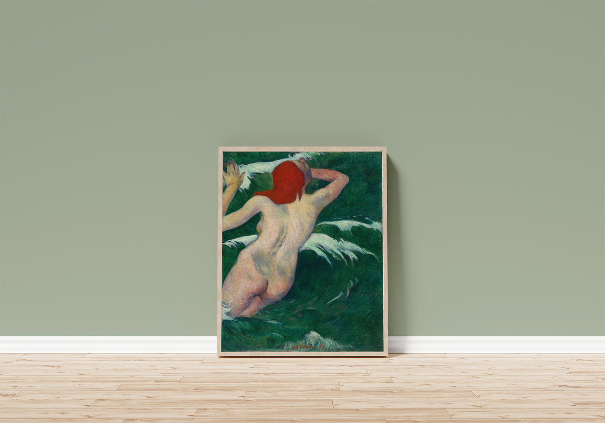 Framed art print of In the Waves (Ondine) by Paul Gauguin, in a light wood frame leaning on a sage green wall above a wooden floor