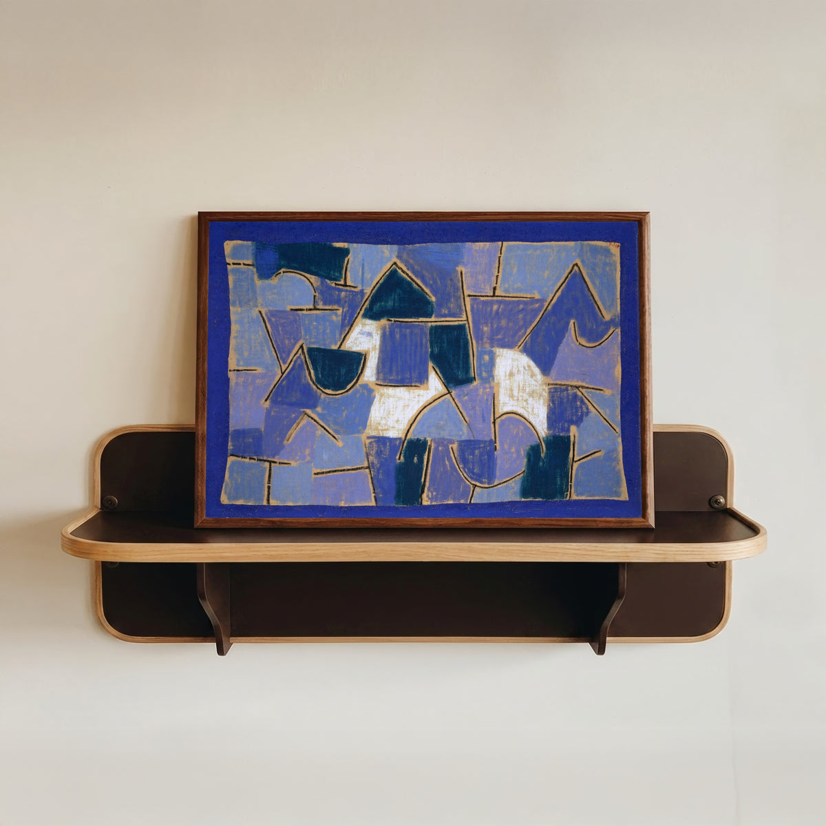 Framed art print of Blue Night by Paul Klee, in a dark wood frame resting on a wall shelf