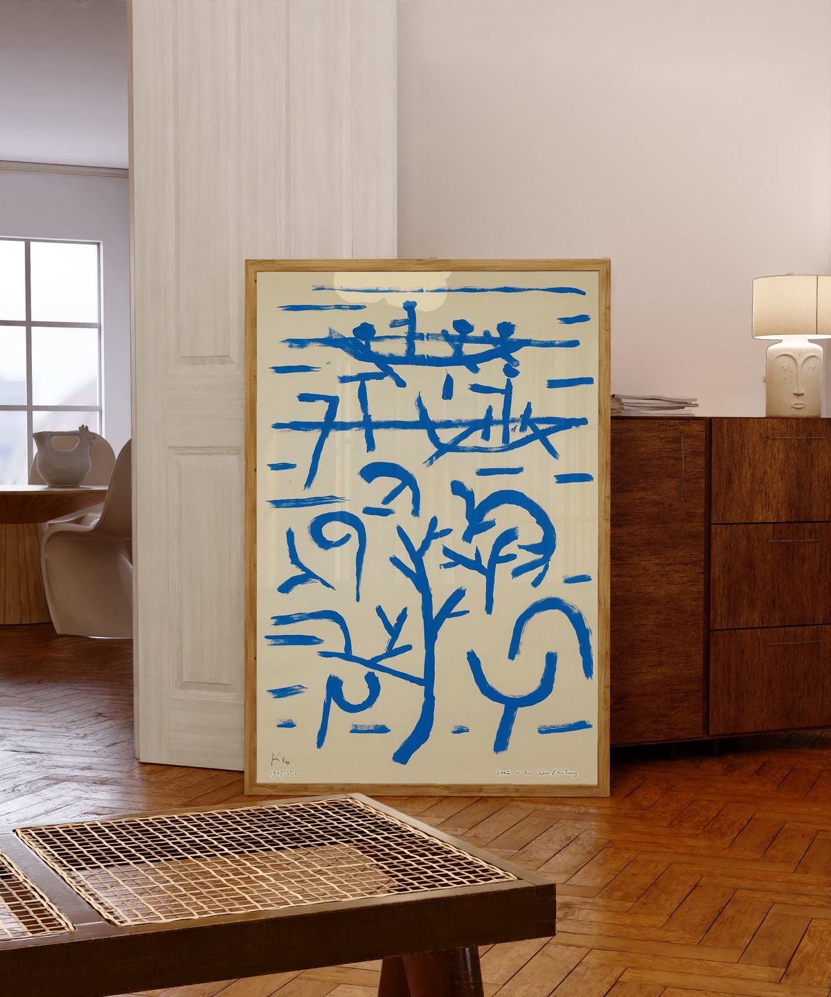 Framed art print of Boats in the Flood (Boote in der Überflutung) by Paul Klee, in a light wood frame leaning in a warm room with a parquet floor