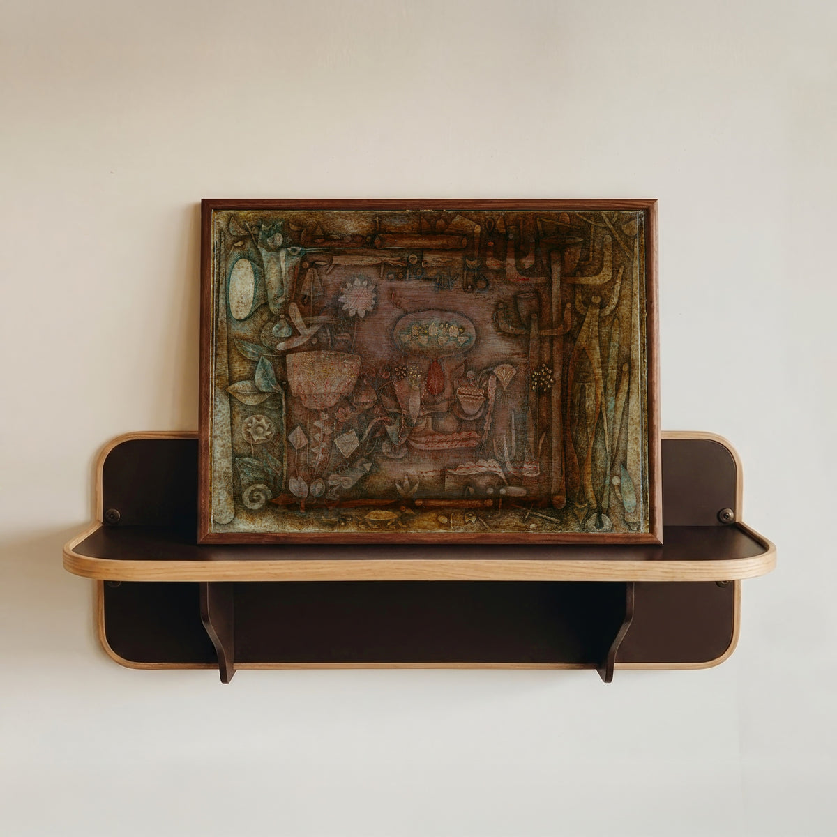 Framed art print of Botanical Theater by Paul Klee, in a dark wood frame resting on a wall shelf