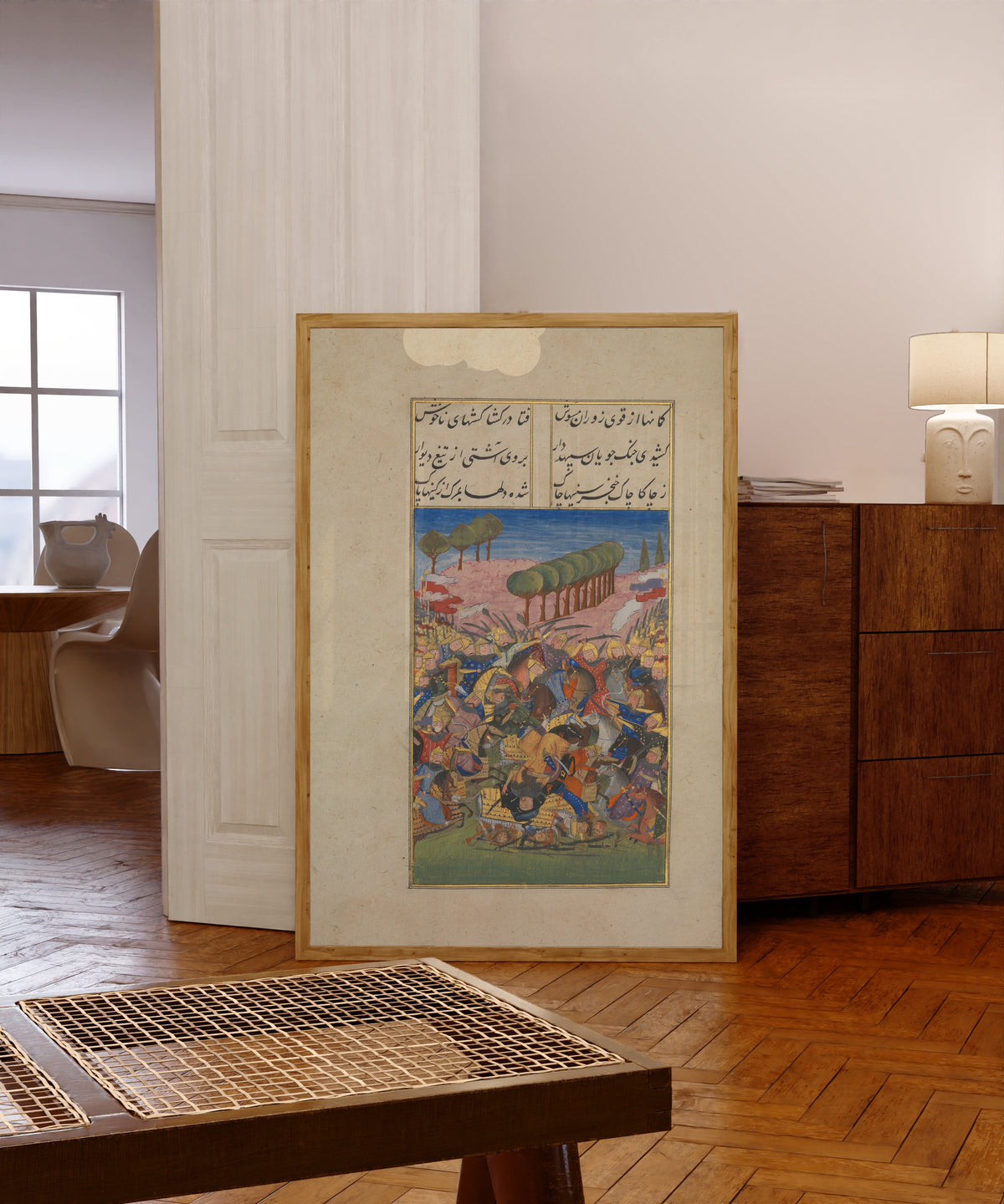 Framed art print of Khusrau and Shirin: A Battle Scene by Suzi, in a light wood frame leaning in a warm room with a parquet floor