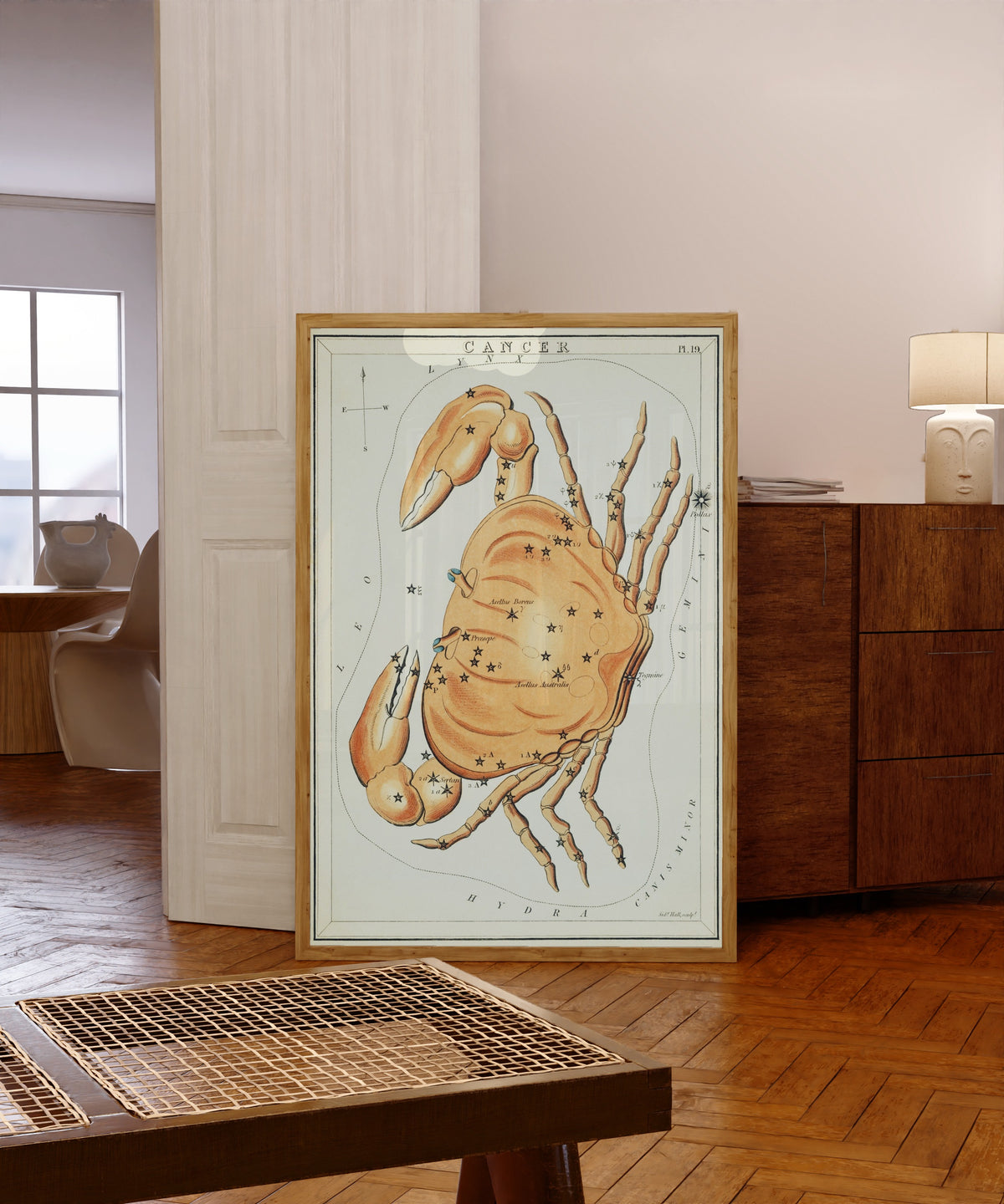 Framed art print of Cancer by Sidney Hall, in a light wood frame leaning in a warm room with a parquet floor