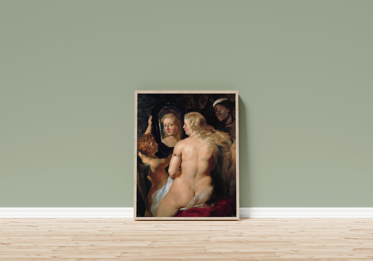 Framed art print of The Toilet of Venus by Peter Paul Rubens, in a light wood frame leaning on a sage green wall above a wooden floor