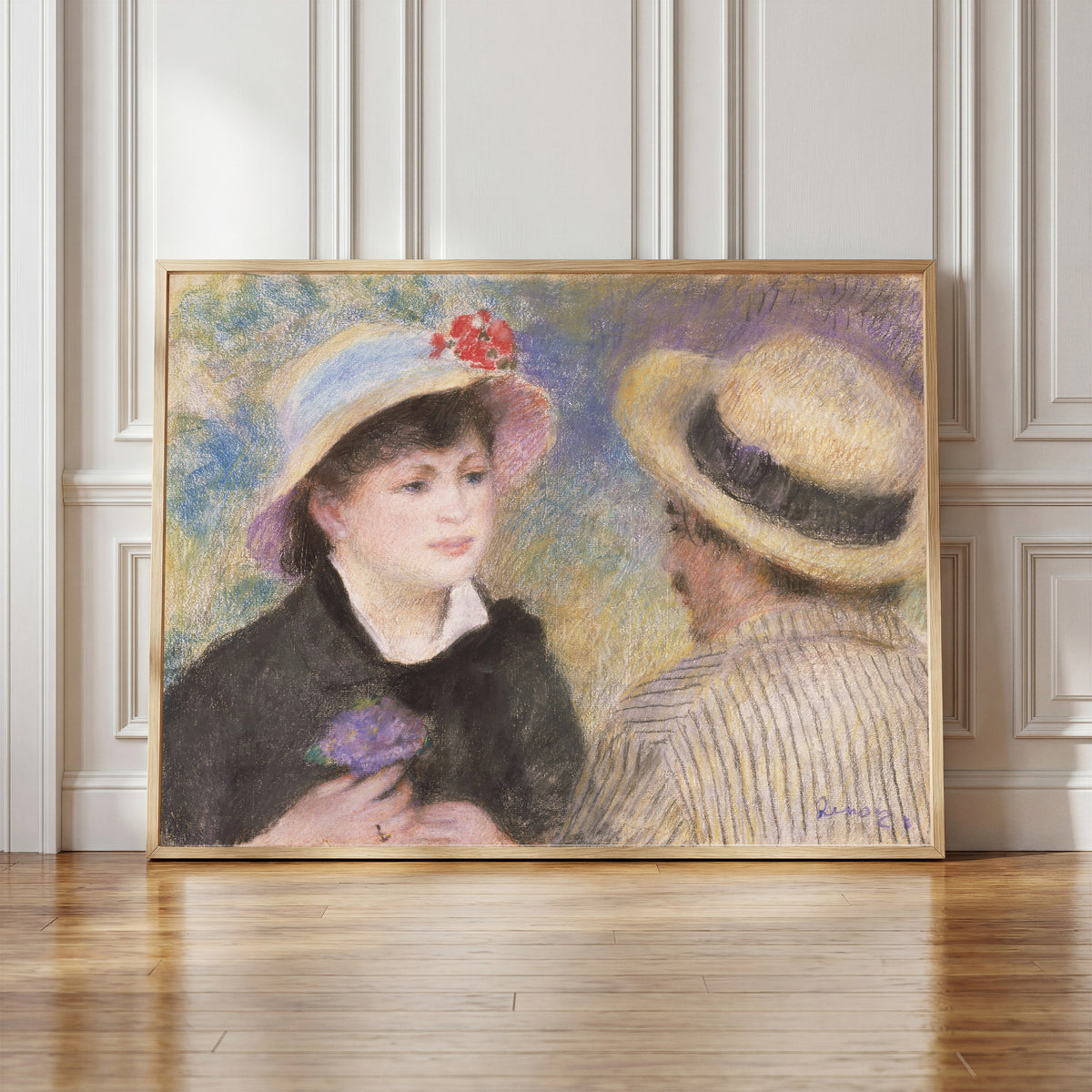 Framed art print of Boating Couple (said to be Aline Charigot and Renoir) by Pierre-Auguste Renoir, in a light wood frame leaning against a panelled white wall