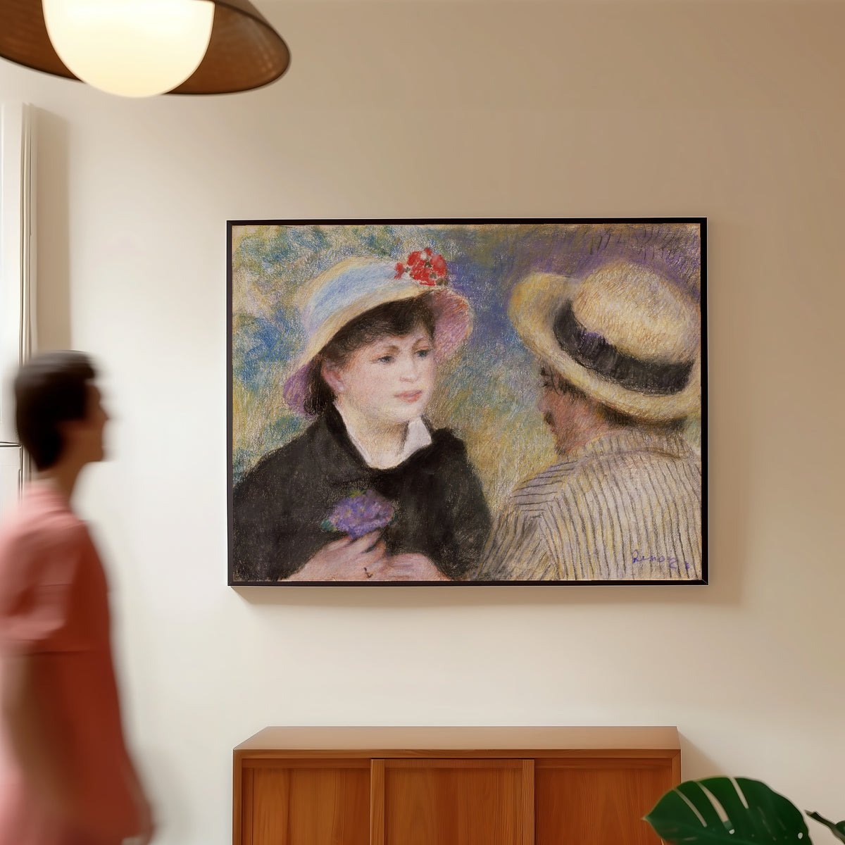 Framed art print of Boating Couple (said to be Aline Charigot and Renoir) by Pierre-Auguste Renoir, in a slim black frame on a warm wall in a sunlit room