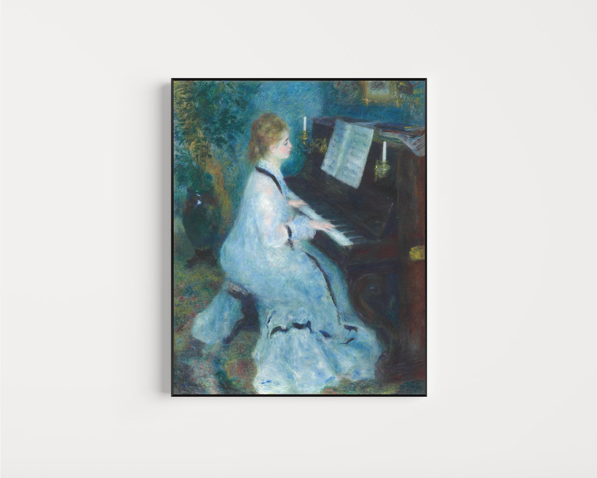 Framed art print of Woman at the Piano by Pierre-Auguste Renoir, in a slim black frame on a plain white wall