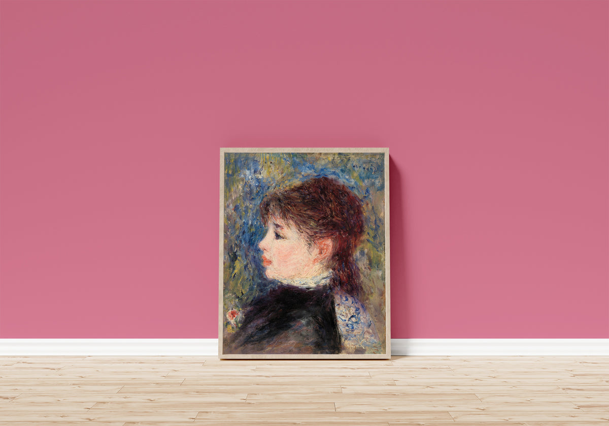 Framed art print of Young Woman with Rose by Pierre-Auguste Renoir, in a light wood frame leaning on a pink wall above a wooden floor