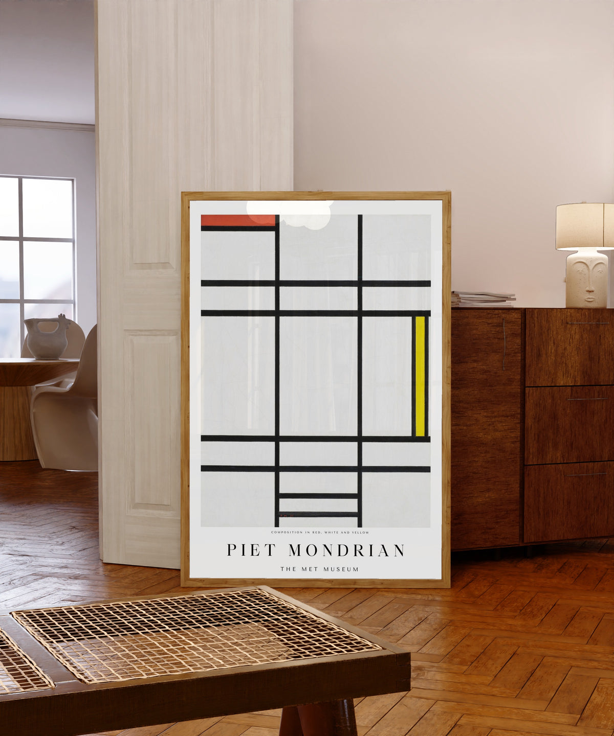 Framed art print of Composition by Piet Mondrian, in a light wood frame leaning in a warm room with a parquet floor