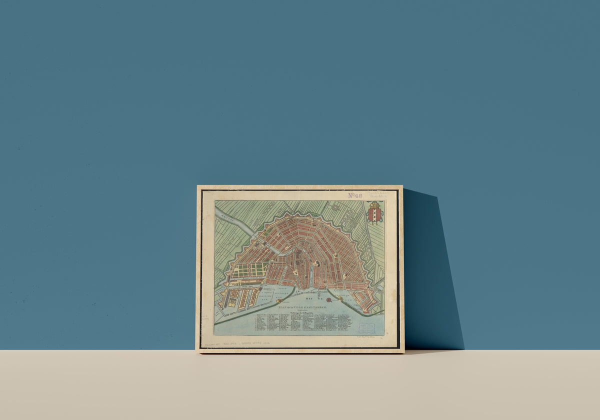 Framed art print of Plan de la Ville d'Amsterdam, in a light wood frame leaning on a blue wall