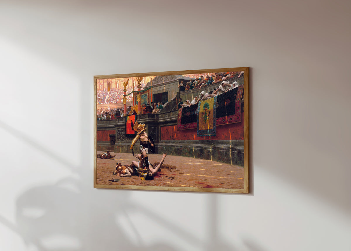 Framed art print of Pollice Verso by Jean-Léon Gérôme, in a light wood frame on a sunlit white wall, seen at a slight angle