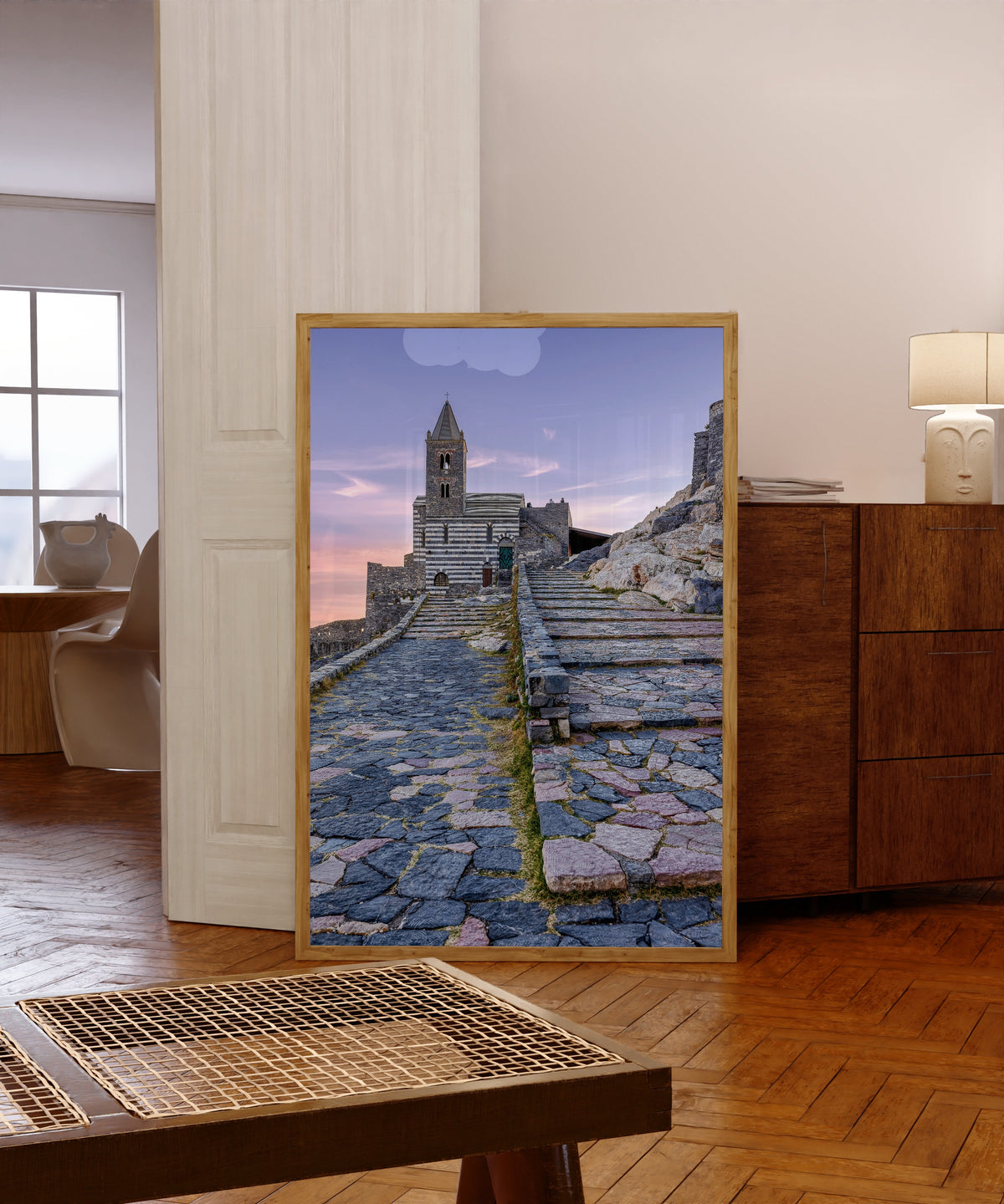 Framed art print of Porto Venere by Pablo Meilán Campagnale, in a light wood frame leaning in a warm room with a parquet floor