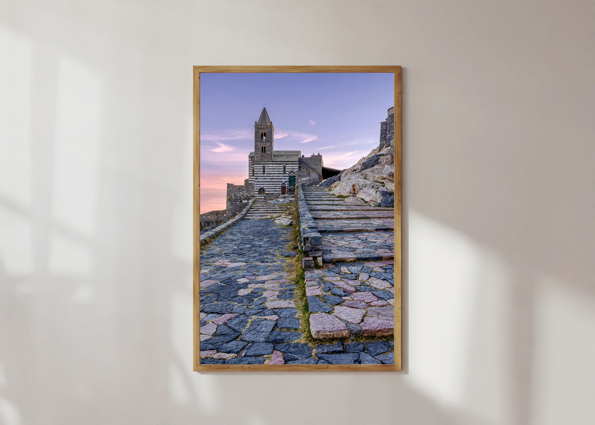 Framed art print of Porto Venere by Pablo Meilán Campagnale, in a light wood frame on a sunlit white wall