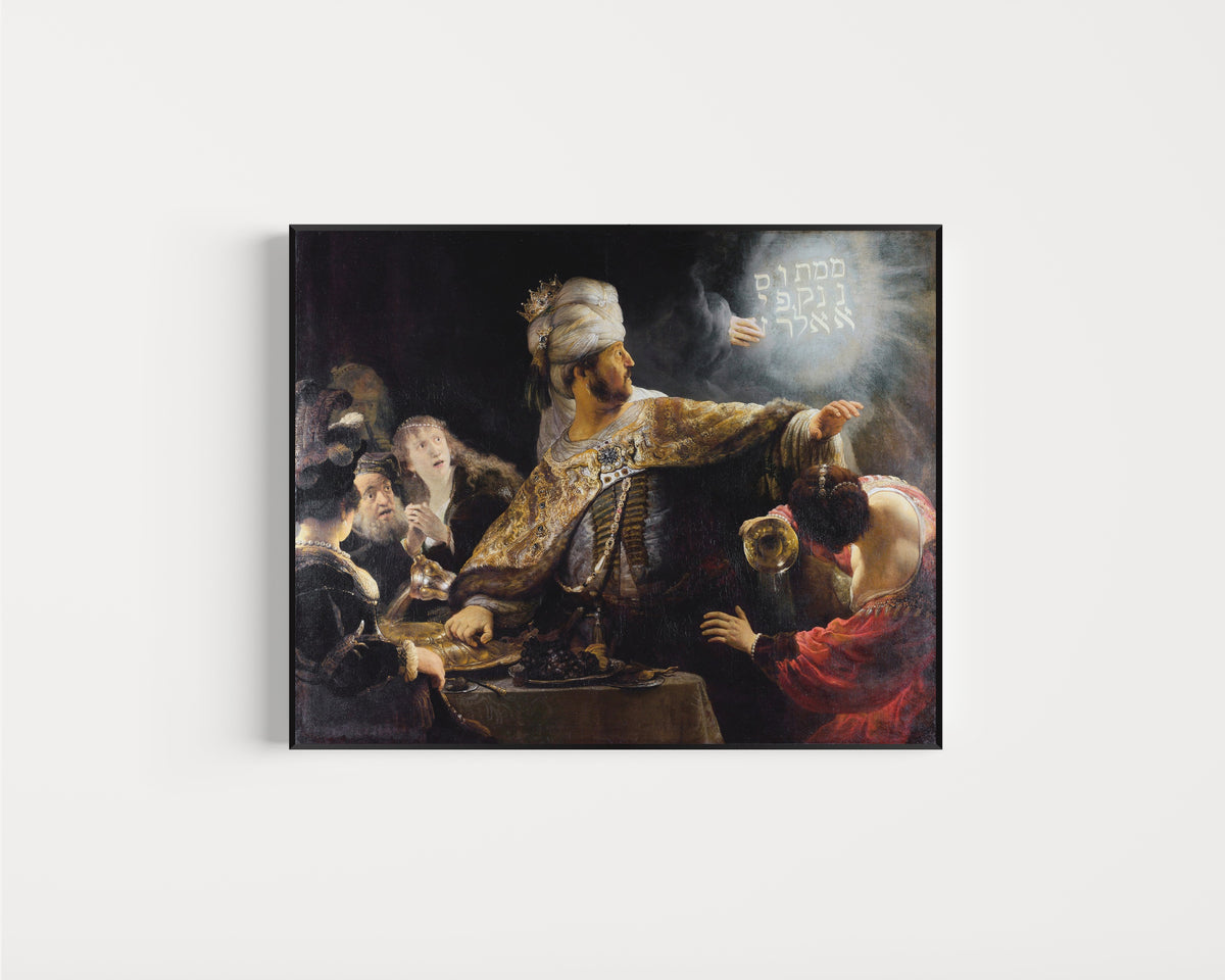 Framed art print of Belshazzar's Feast by Rembrandt van Rijn, in a slim black frame on a plain white wall
