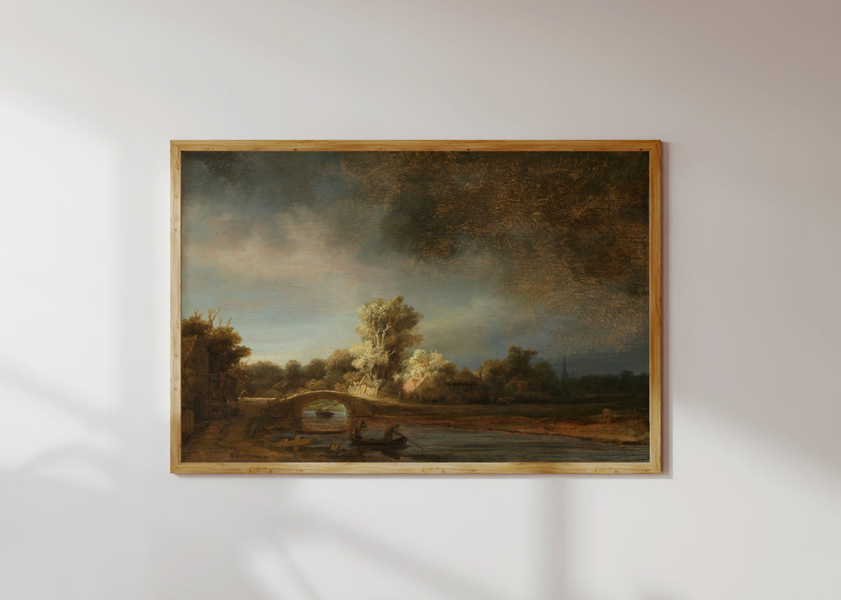 Framed art print of Landscape with a Stone Bridge by Rembrandt van Rijn, in a light wood frame on a sunlit white wall