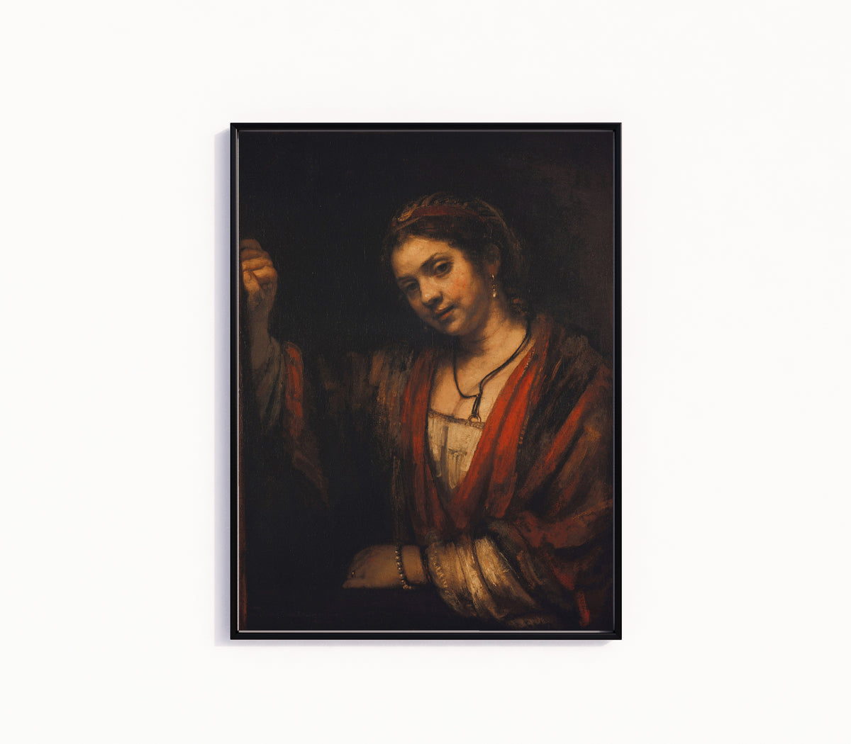 Framed art print of Young Woman at the Open Top Door by Rembrandt van Rijn, in a slim black frame on a plain white wall