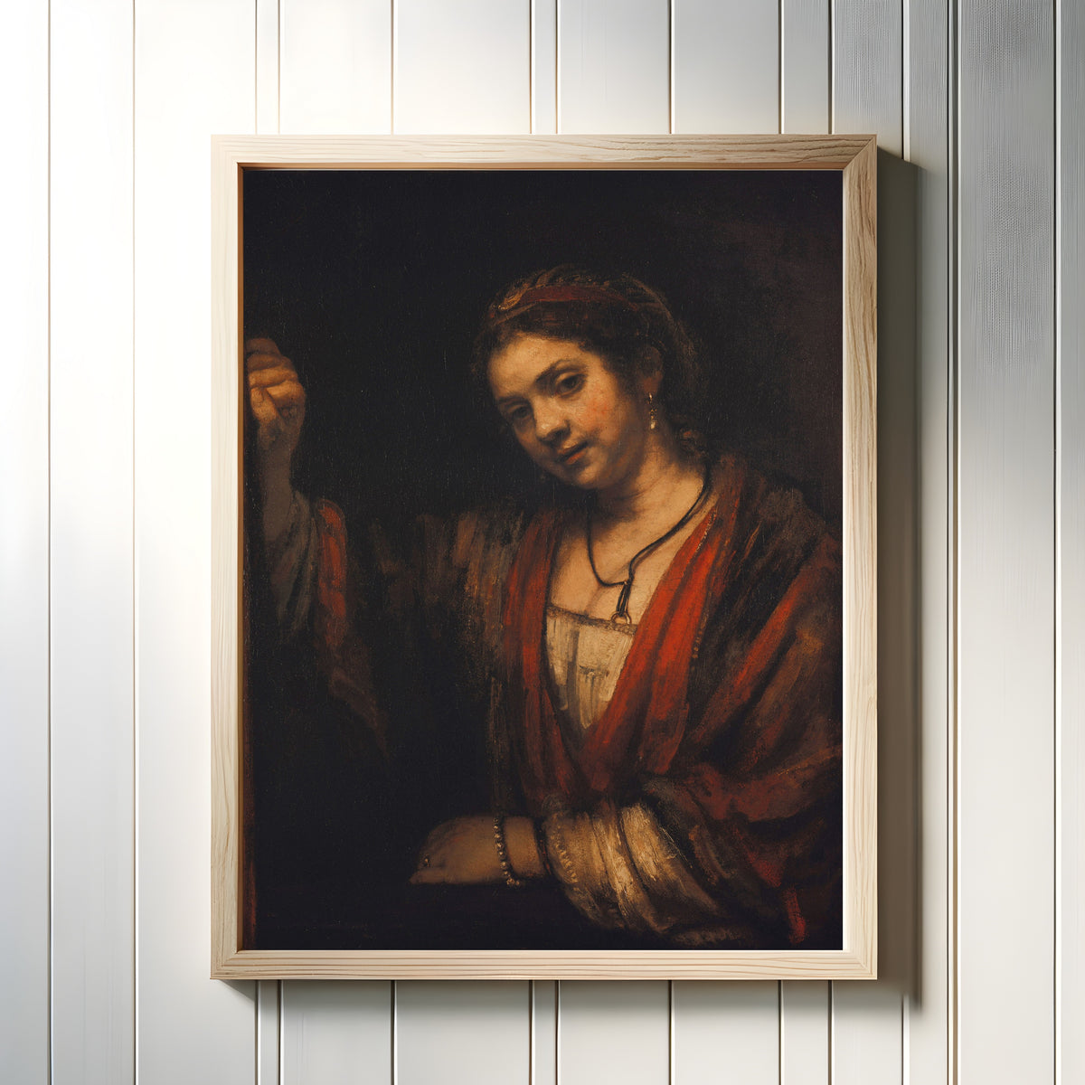 Framed art print of Young Woman at the Open Top Door by Rembrandt van Rijn, in a light wood frame on a white panelled wall