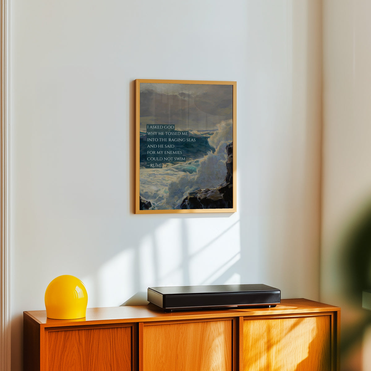 Framed art print of Raging Seas by Rumi, in a light wood frame on a white wall above an orange sideboard