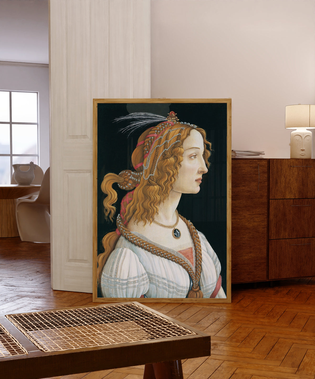 Framed art print of Idealized Portrait of a Lady by Sandro Botticelli, in a light wood frame leaning in a warm room with a parquet floor