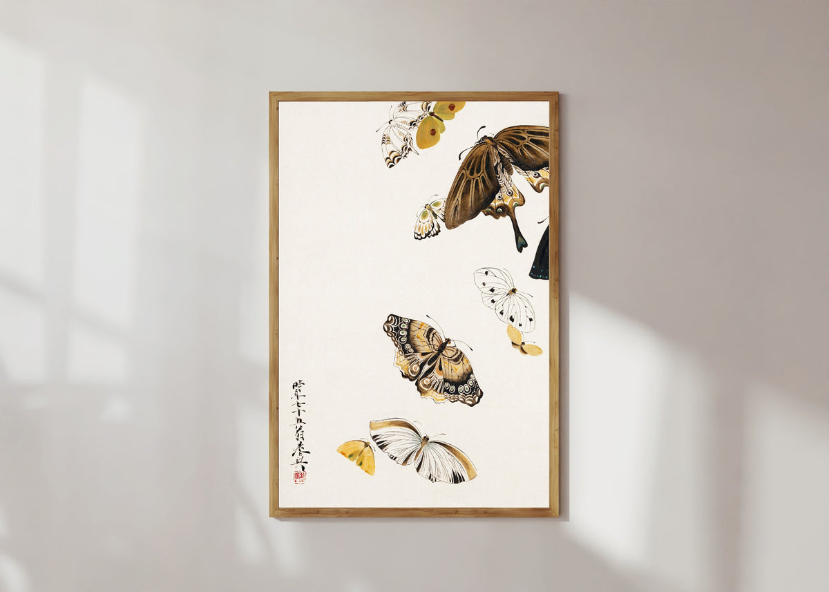 Framed art print of Butterflies by Shibata Zeshin, in a light wood frame on a sunlit white wall