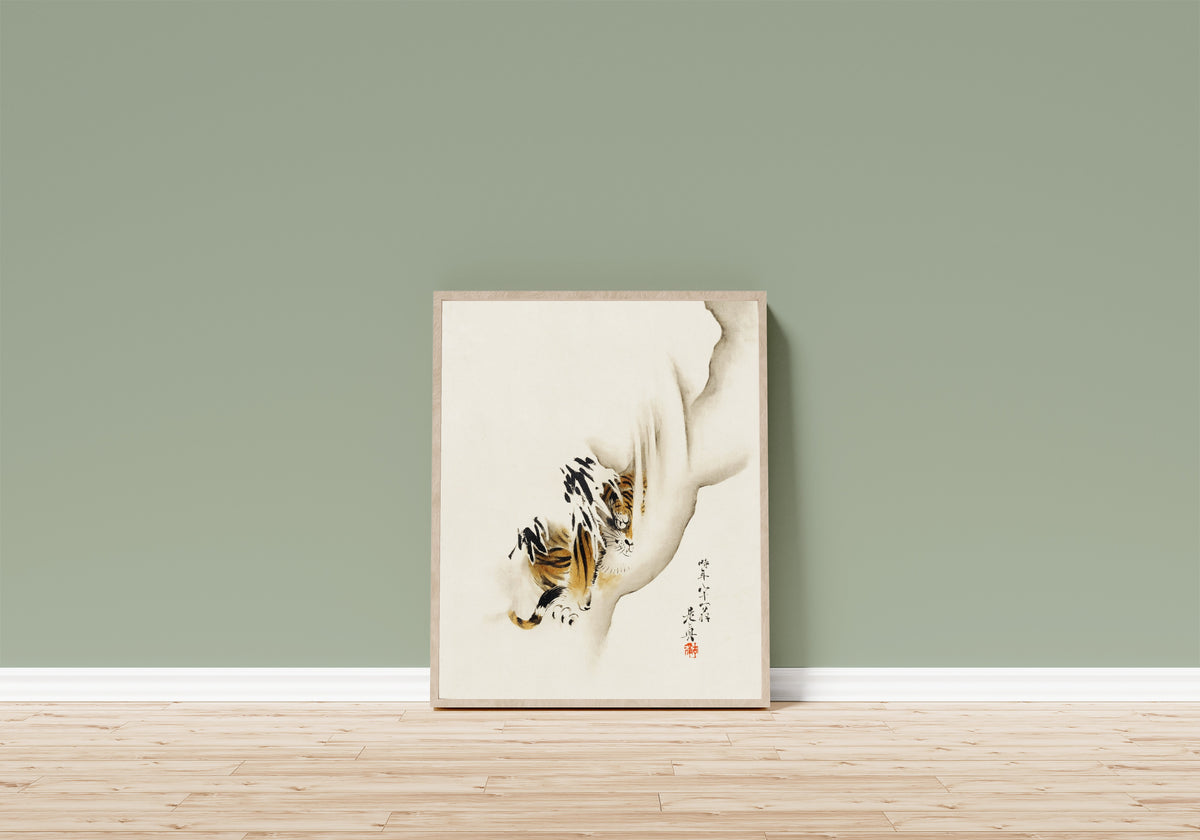Framed art print of Tiger by Shibata Zeshin, in a light wood frame leaning on a sage green wall above a wooden floor