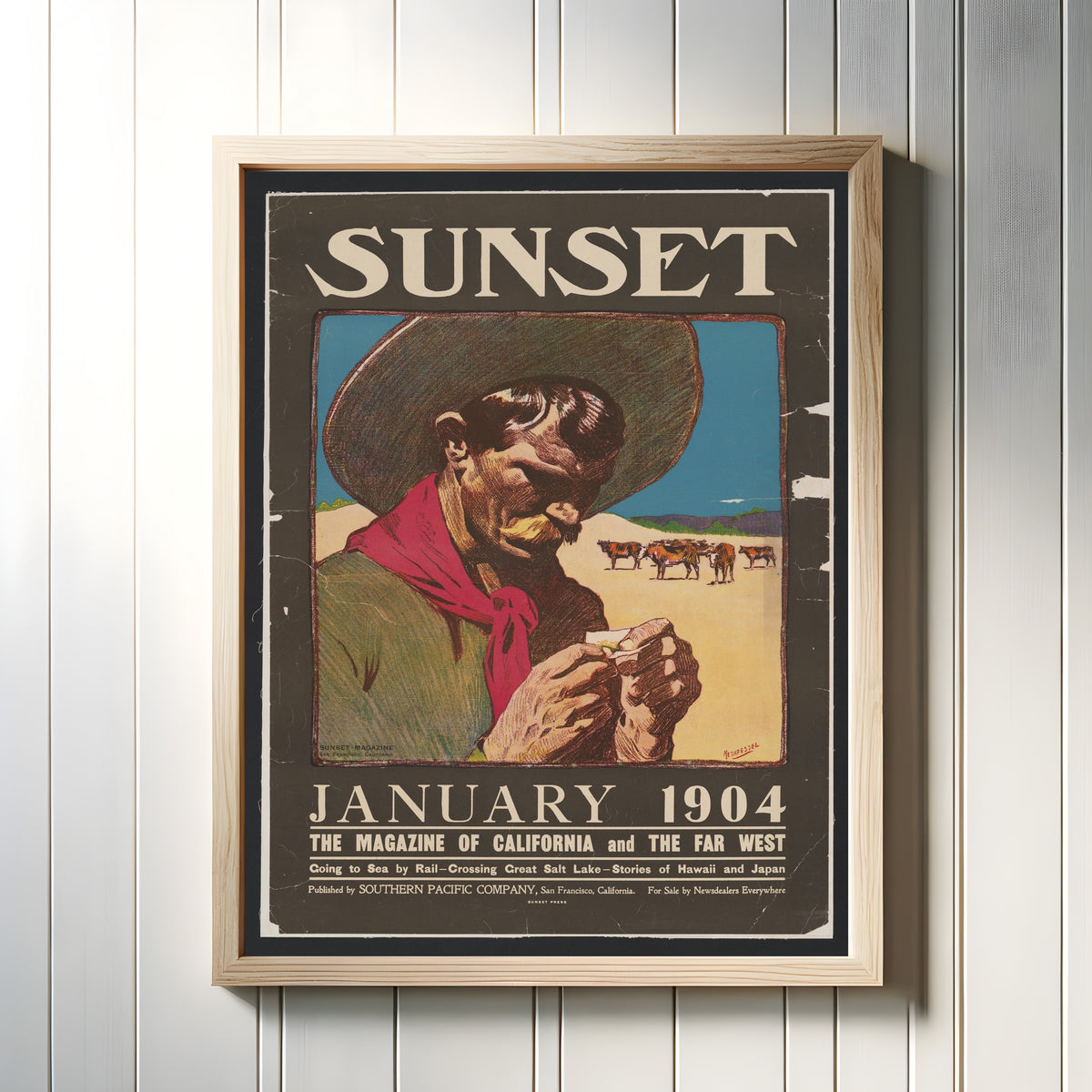 Framed art print of Sunset Magazine Cowboy (January 1904) by Maynard Dixon, in a light wood frame on a white panelled wall