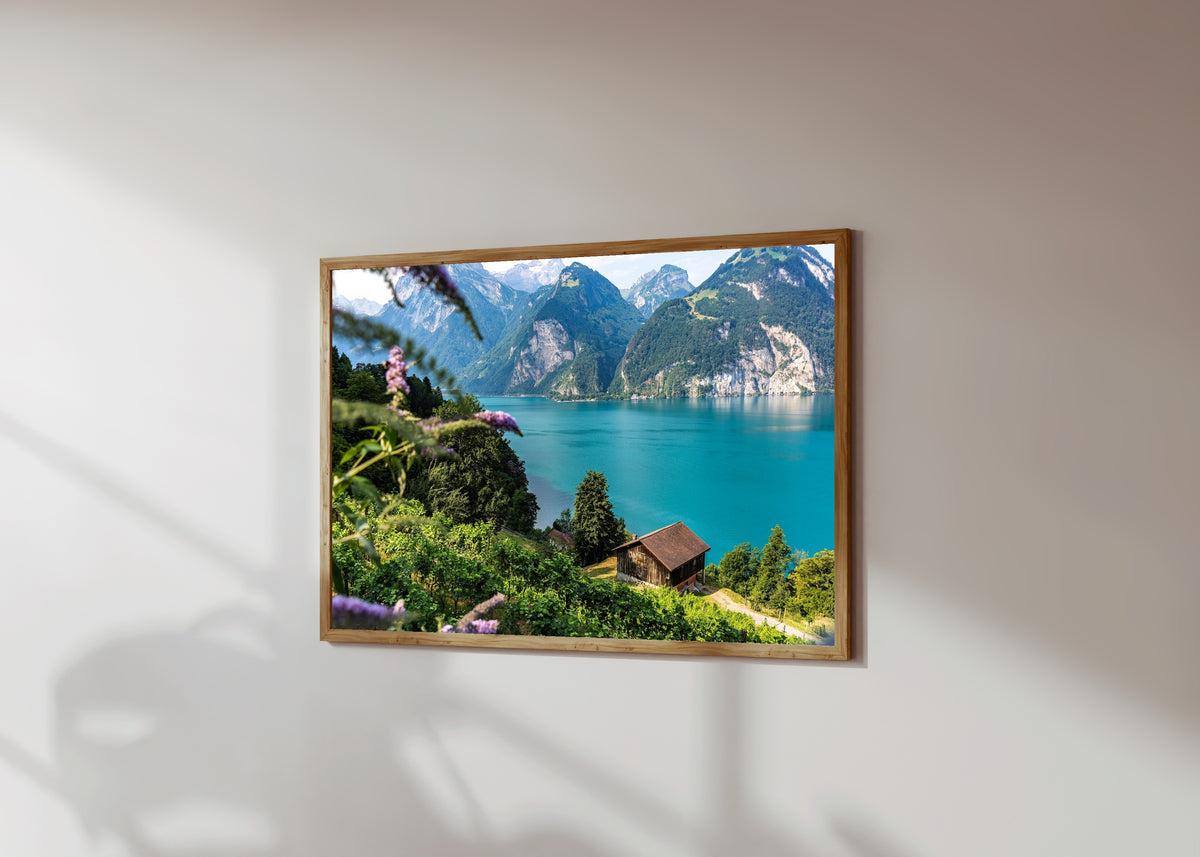 Framed art print of Tellsplatte (Switzerland) by Daniela Faust, in a light wood frame on a sunlit white wall, seen at a slight angle