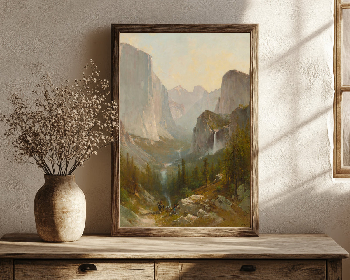 Framed art print of Yosemite Valley by Thomas Hill, in a dark wood frame leaning on a rustic console beside dried flowers