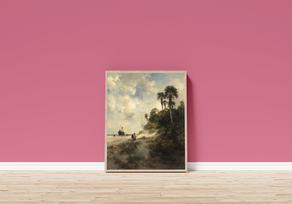 Framed art print of Fort George Island, Florida by Thomas Moran, in a light wood frame leaning on a pink wall above a wooden floor