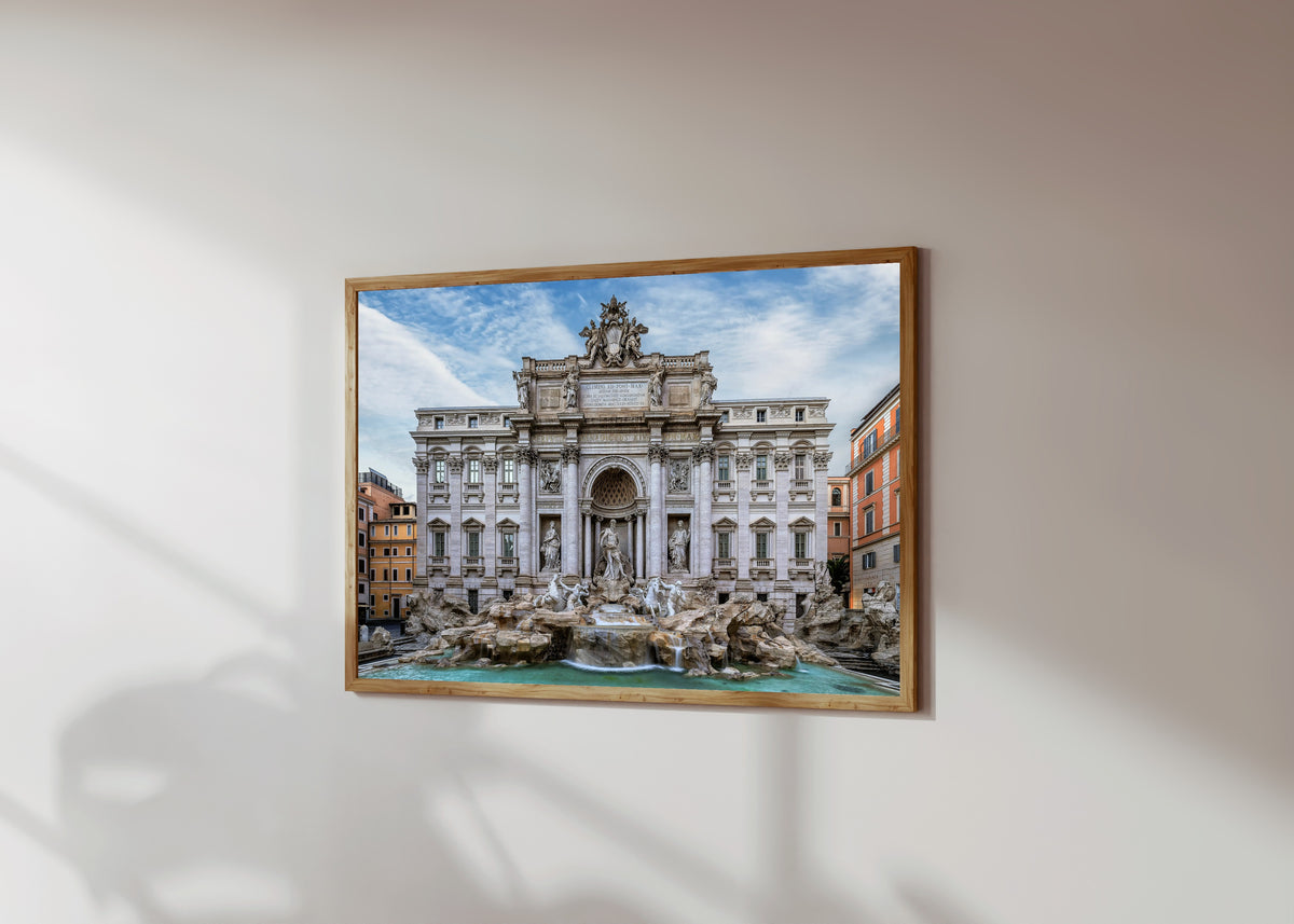 Framed art print of Trevi Fountain (Rome) by Pablo Meilán Campagnale, in a light wood frame on a sunlit white wall, seen at a slight angle