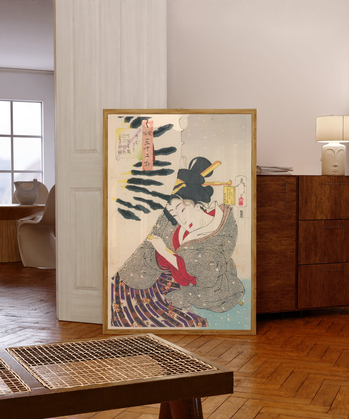 Framed art print of Fūzoku sanjūni sō: Looks Cold (Tenpō-era… by Tsukioka Yoshitoshi, in a light wood frame leaning in a warm room with a parquet floor