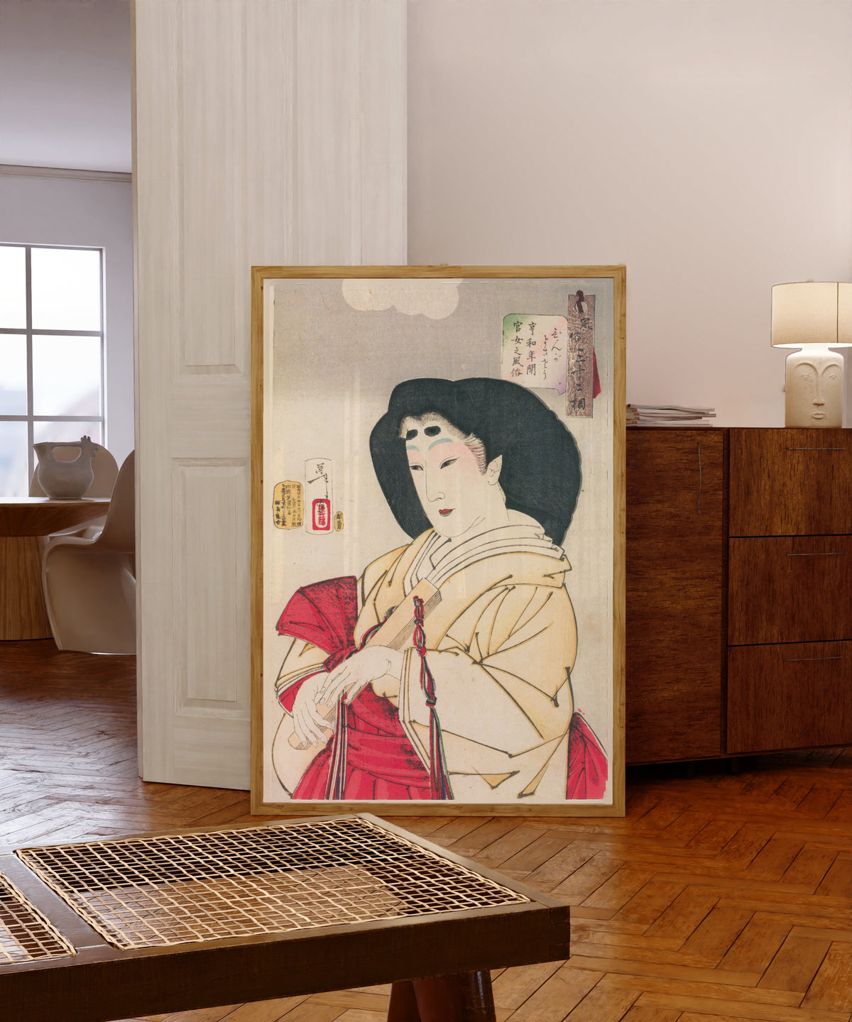 Framed art print of Looks Refined (Kyōwa-era Court Lady) by Tsukioka Yoshitoshi, in a light wood frame leaning in a warm room with a parquet floor