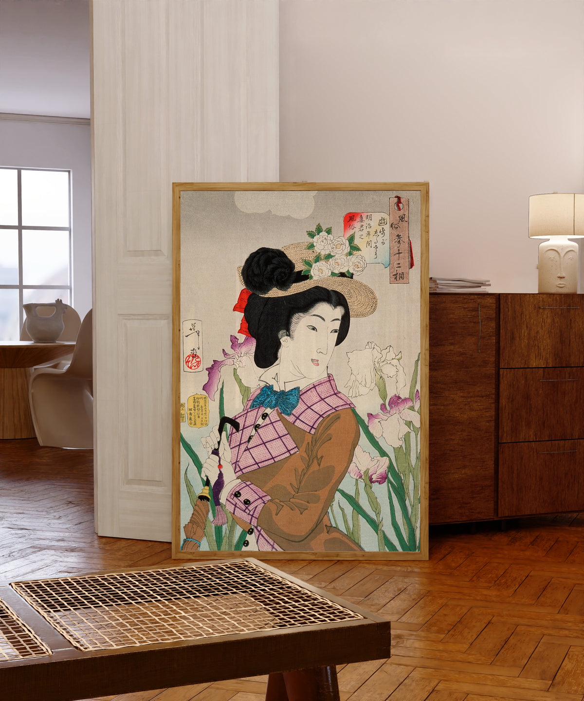Framed art print of Preparing to Take a Stroll; The Wife of a… by Tsukioka Yoshitoshi, in a light wood frame leaning in a warm room with a parquet floor