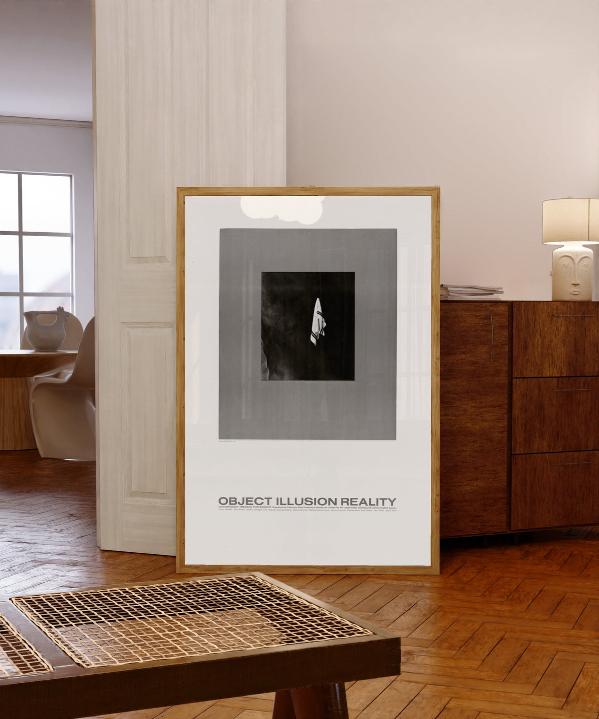 Framed art print of Object, Illusion, Reality by USIA, in a light wood frame leaning in a warm room with a parquet floor