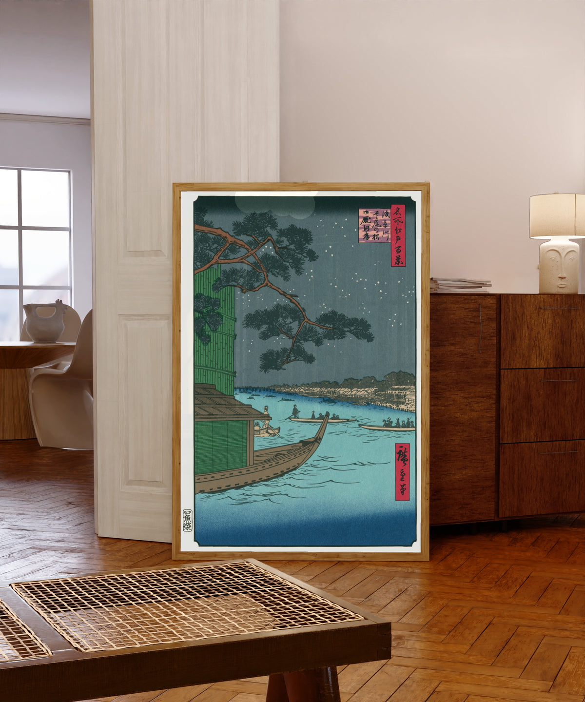 Framed art print of 100 Views of Edo: Asakusa River, Shubi Pine… by Utagawa Hiroshige, in a light wood frame leaning in a warm room with a parquet floor