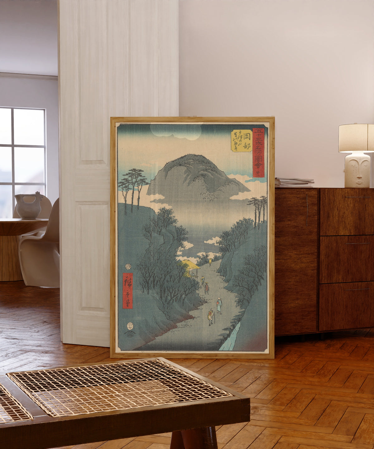Framed art print of Famous Sights of the Fifty-three Stations: Okabe by Utagawa Hiroshige, in a light wood frame leaning in a warm room with a parquet floor