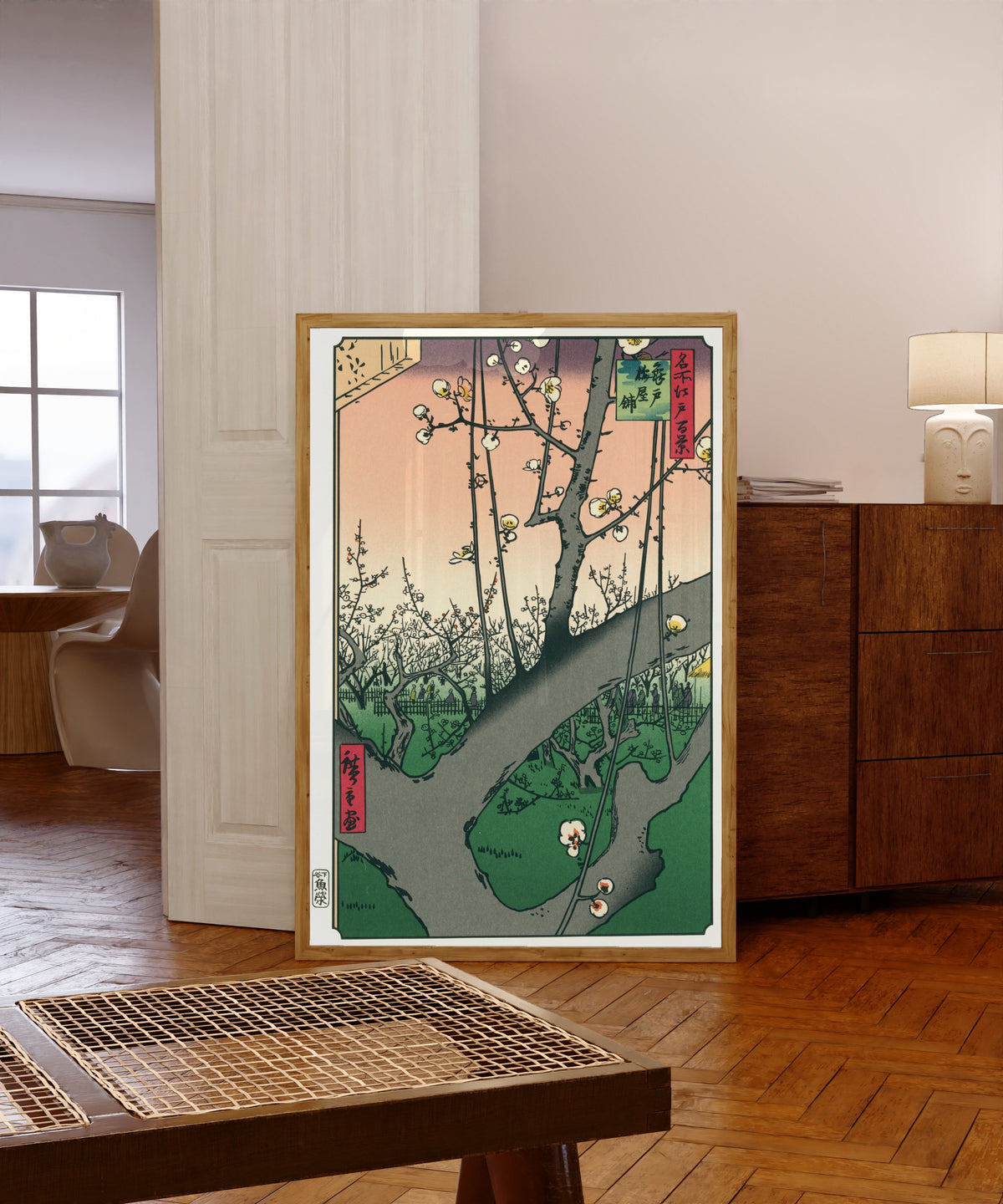 Framed art print of Plum Park in Kameido by Utagawa Hiroshige, in a light wood frame leaning in a warm room with a parquet floor