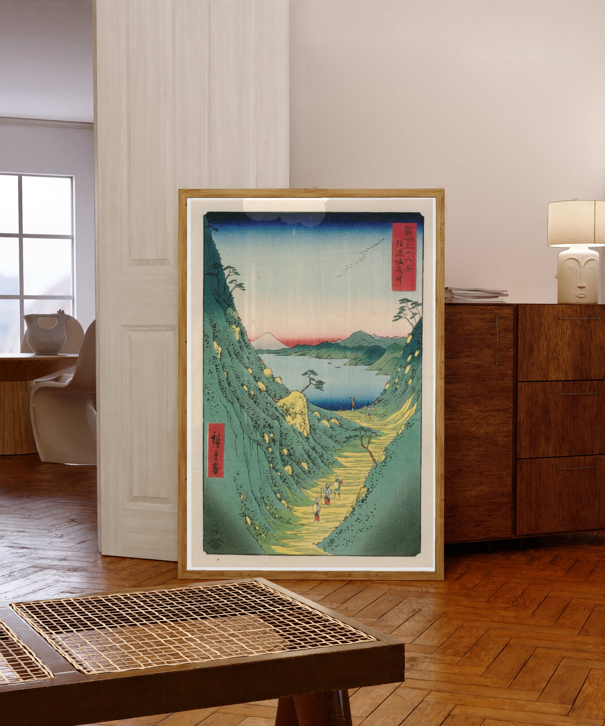 Framed art print of Shiojiri Pass in Shinano Province by Utagawa Hiroshige, in a light wood frame leaning in a warm room with a parquet floor