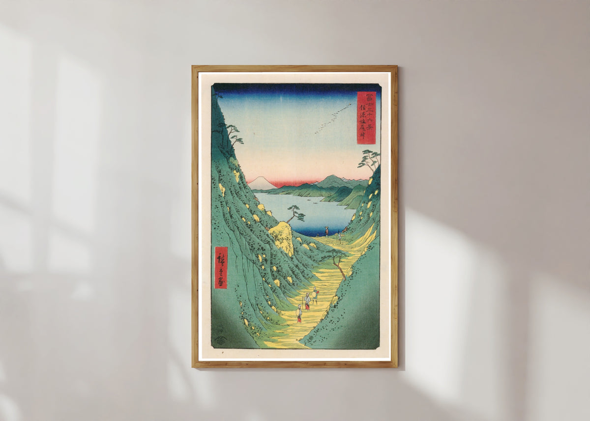 Framed art print of Shiojiri Pass in Shinano Province by Utagawa Hiroshige, in a light wood frame on a sunlit white wall