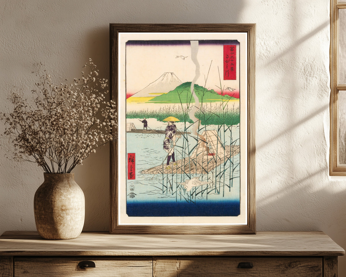Framed art print of The Sagami River by Utagawa Hiroshige, in a dark wood frame leaning on a rustic console beside dried flowers