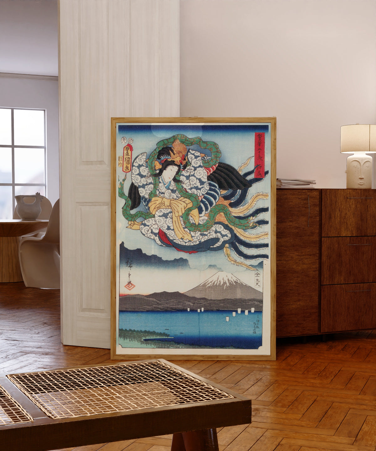 Framed art print of Fifty-three Stations by Two… by Utagawa Hiroshige & Utagawa Kunisada, in a light wood frame leaning in a warm room with a parquet floor